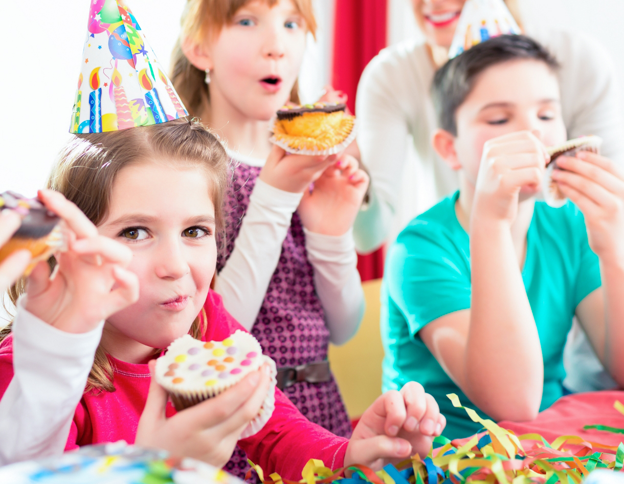 Kinder feiern eine Geburtstagsfeier und essen Muffins